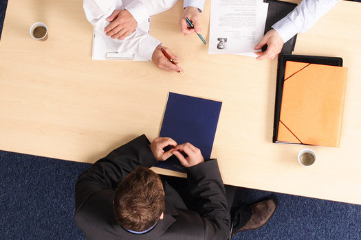 man sitting across the table from two job interviewers