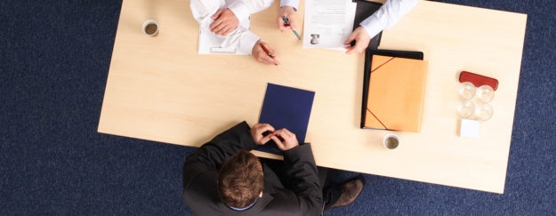 man sitting across the table from two job interviewers