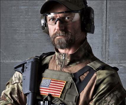 tom spooner in combat gear holding rifle