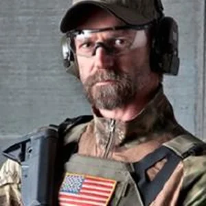 tom spooner in combat gear holding rifle